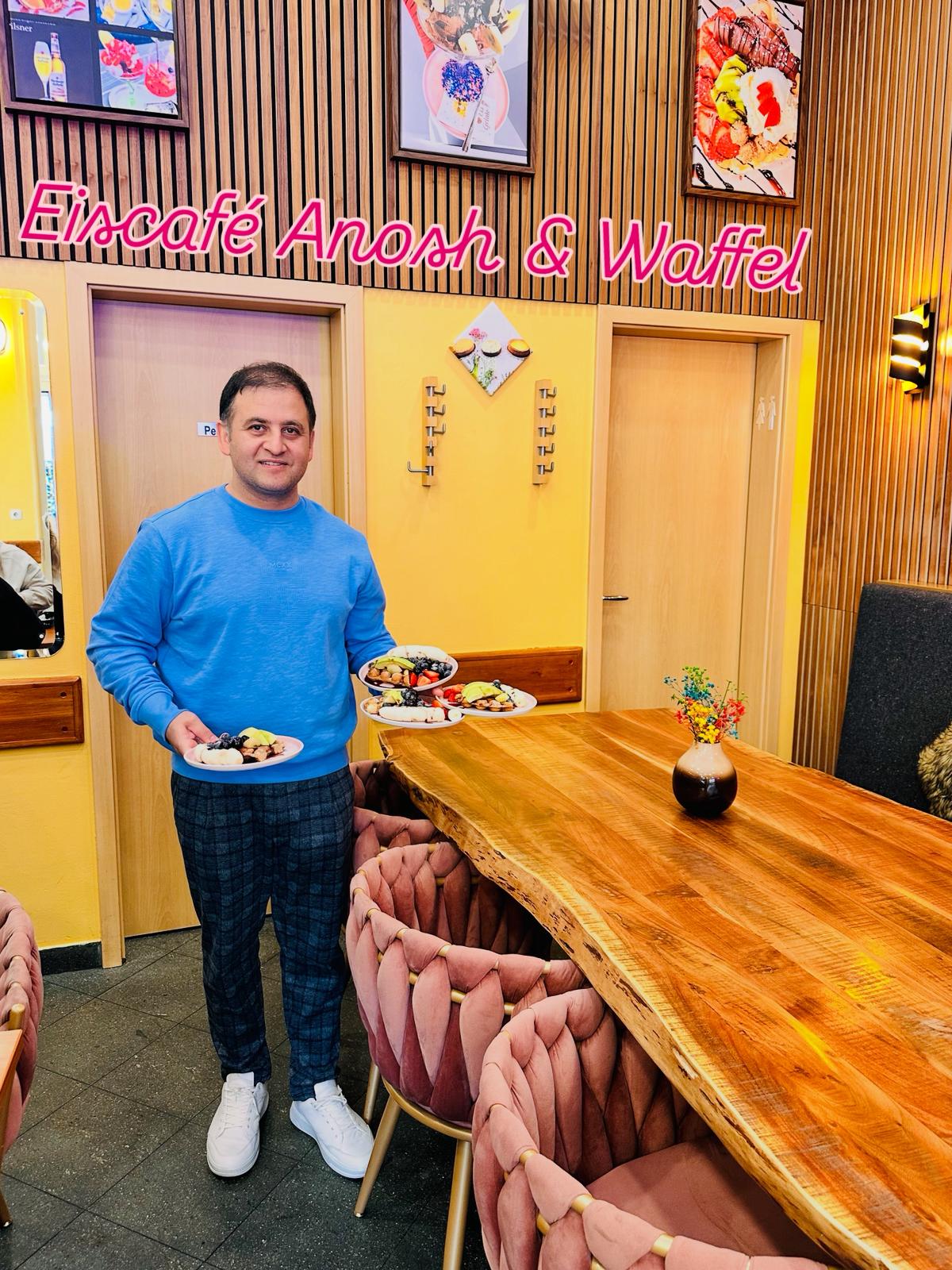 Inhaber Anosh mit drei Waffel-Tellern im Eiscafé